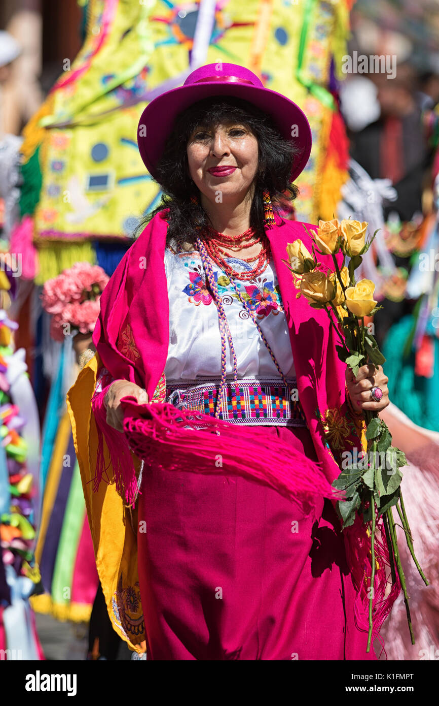 Juni 17, 2017 Pujili, Ecuador: Frau mit einem bunten Kostüm an der jährlichen Corpus Christi Parade hlding Blumen marschieren Stockfoto