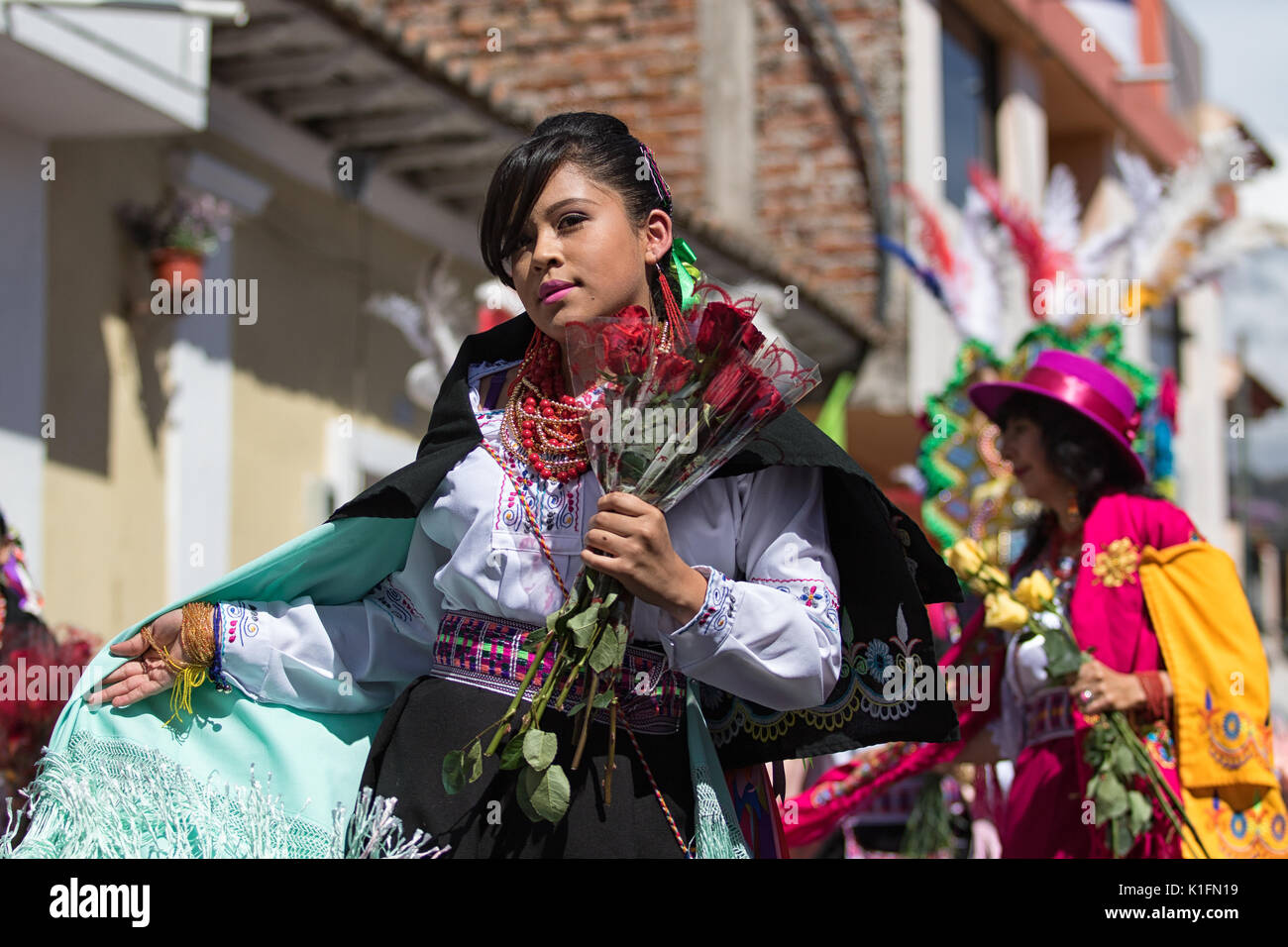 Juni 17, 2017 Pujili, Ecuador: Frau mit einem bunten Kostüm an der jährlichen Corpus Christi parade Blumen Holding marschieren Stockfoto