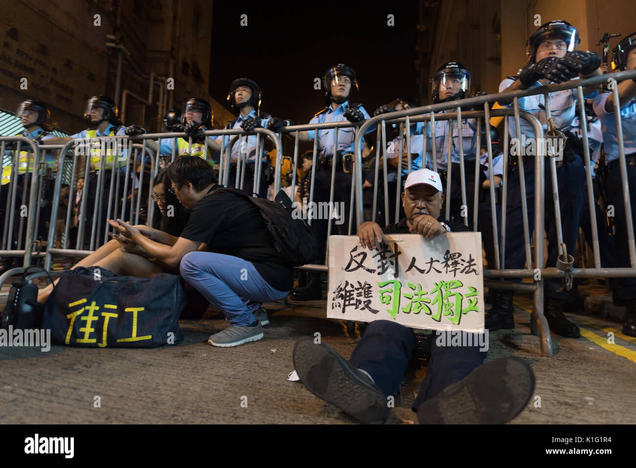 Ein Mann sitzt, bevor die Polizei mit einem Board fordern den Respekt der "Ein Land zwei Systeme" in Hongkong. Stockfoto