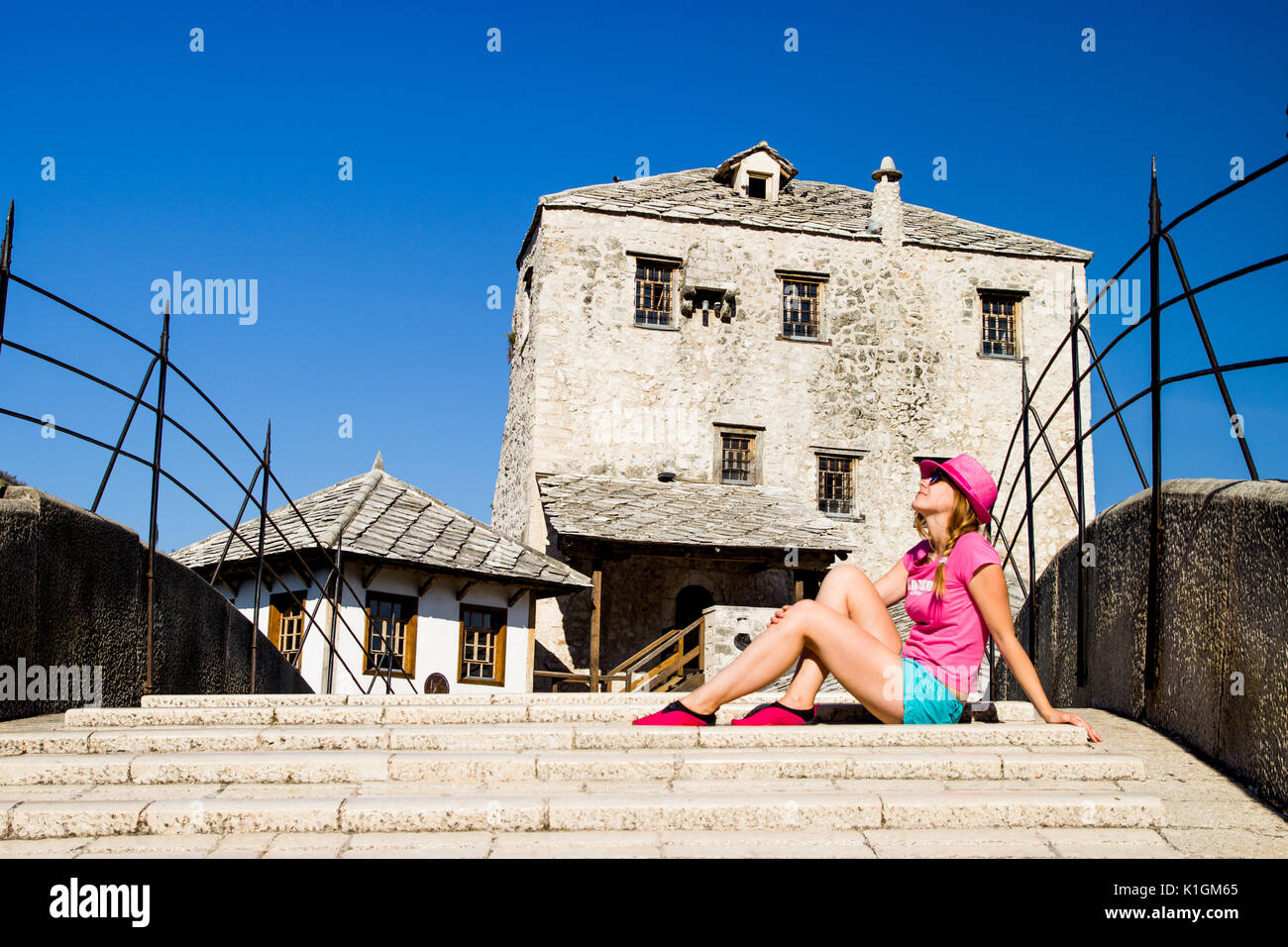 Pretty Girl in Red Hat Sitze auf einer Brücke Mostar Bosnien Stockfoto