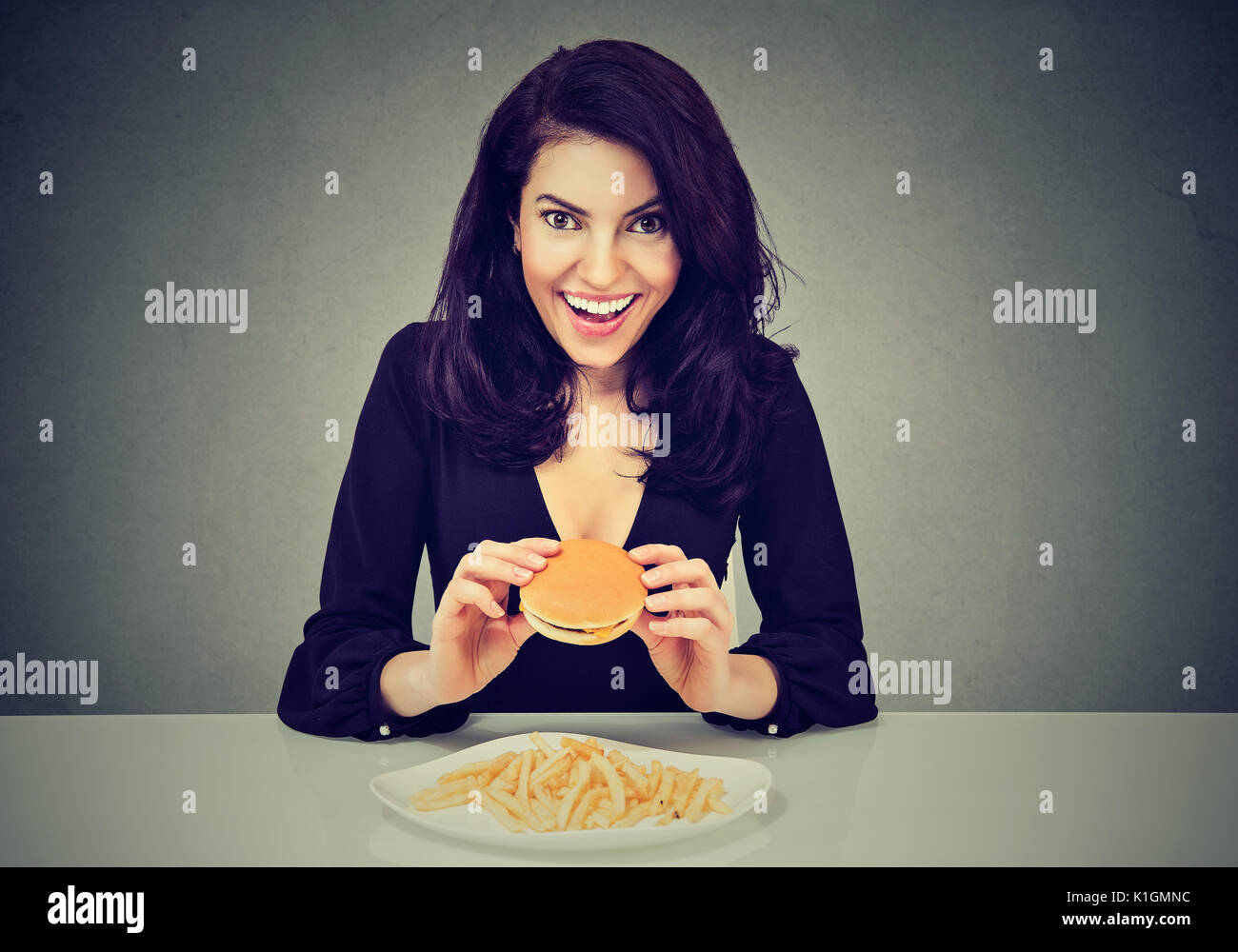 Sie mag fast food. Glückliche Frau essen Cheeseburger und Pommes frites Stockfoto
