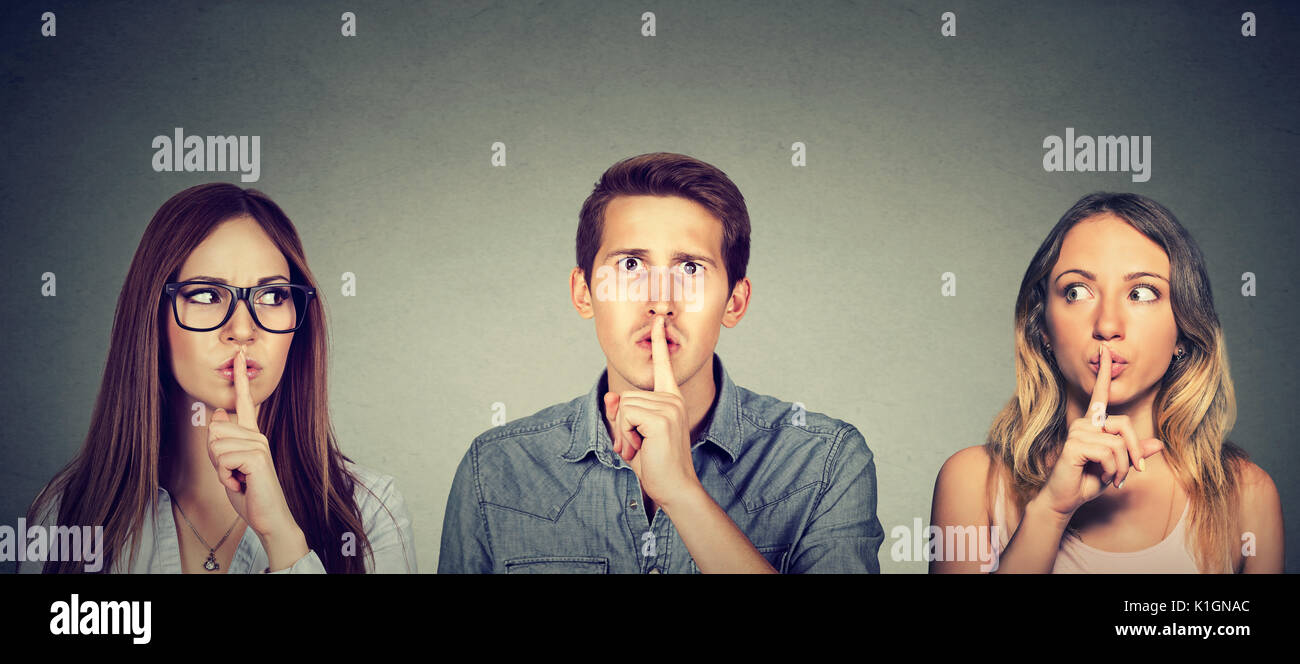 Geheimnisvolle Leute Mann und zwei Frauen mit dem Finger auf die Lippen Geste Stockfoto