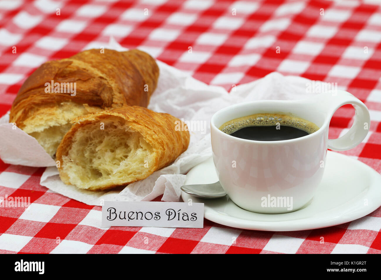 Buenos Dias (Guten Morgen in Spanisch) Karte mit Tasse Kaffee und Croissant auf kariertem Tuch Stockfoto