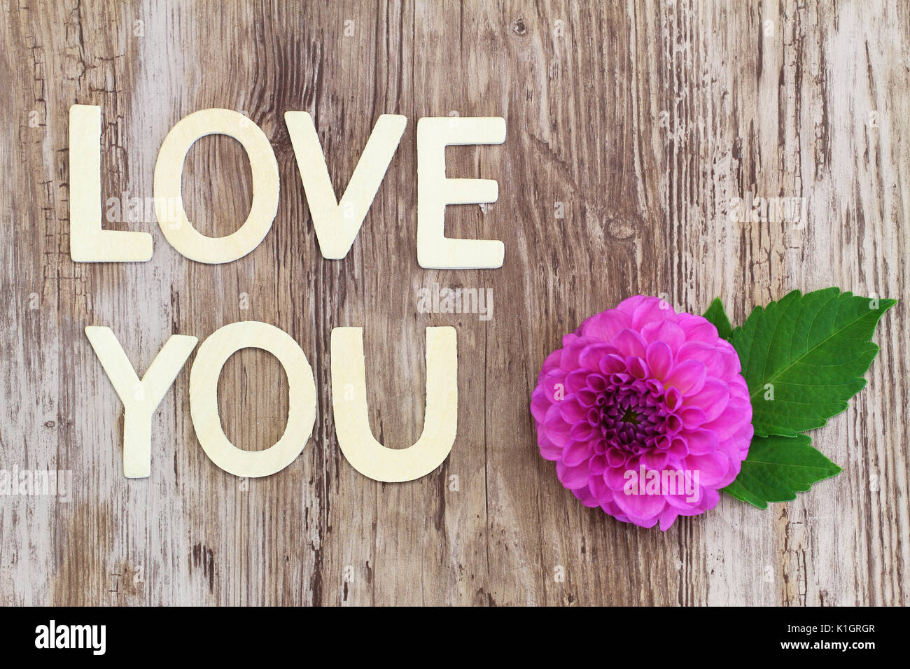 Liebe dich mit Holz Buchstaben auf rustikale Oberfläche und rosa Dahlie geschrieben Stockfoto