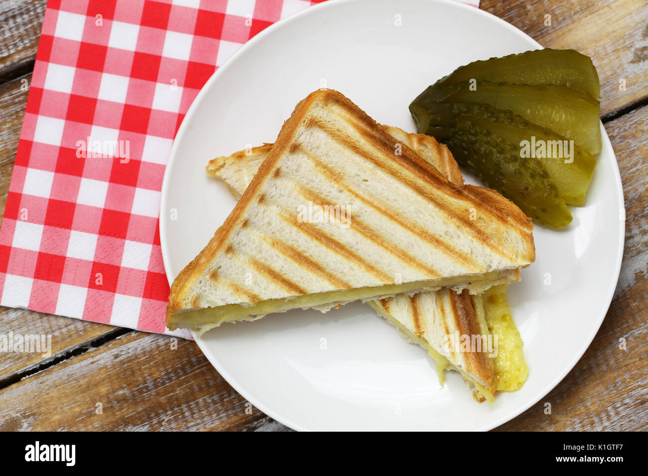 Zwei Stücke von Toast mit geschmolzenem Käse mit Gurke auf der Seite Stockfoto