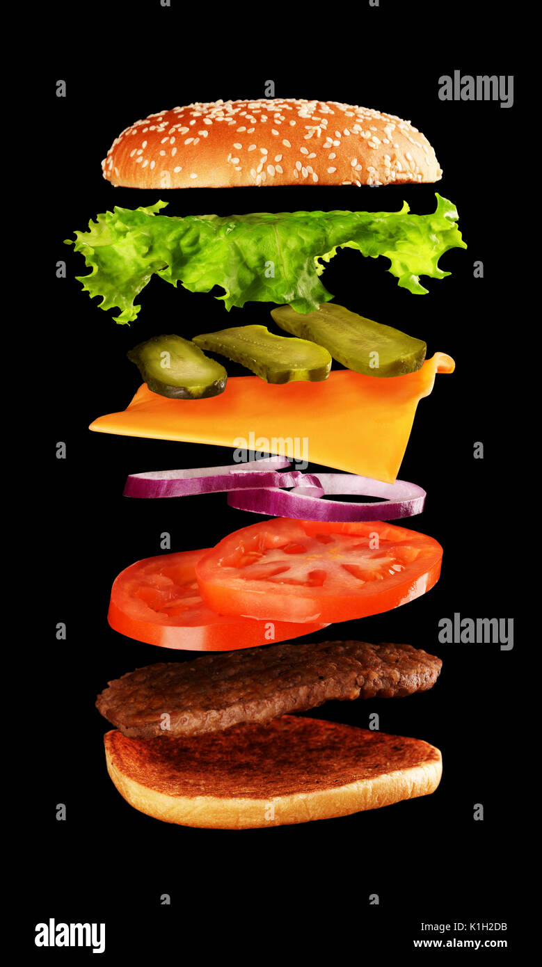 Big leckere hausgemachte Burger mit fliegenden Zutaten auf schwarzem Hintergrund. Stockfoto