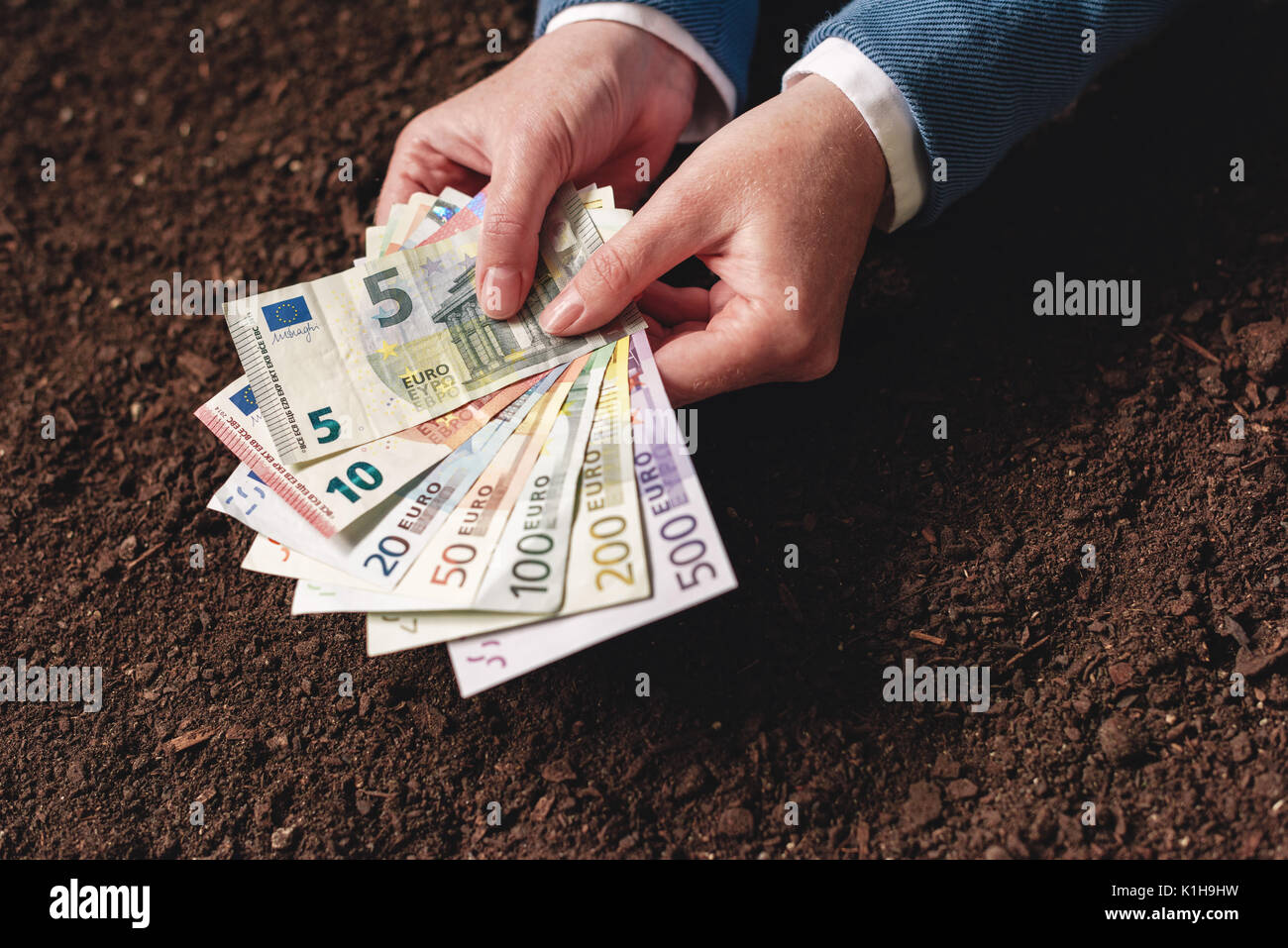 Bank Darlehen für die landwirtschaftliche Tätigkeit in Euro-banknoten, Geschäftsfrau im eleganten Anzug mit europäischen Währung Bargeld über fruchtbaren Boden Stockfoto