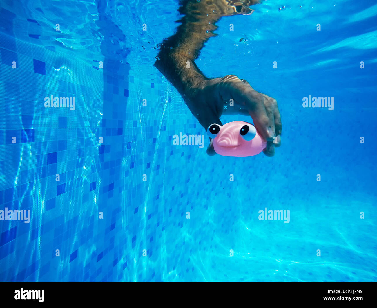 Mann spielt mit generischen Kautschuk Fisch Spielzeug im Schwimmbad, im Sommer Aktivität und Genuss, unter Wasser geschossen Stockfoto