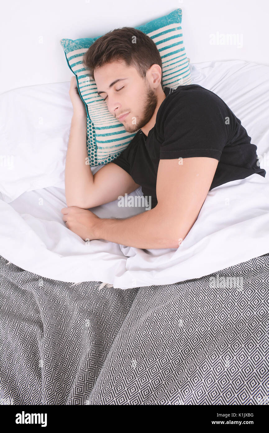 In der Nähe von attraktiven jungen Mann schlafen auf ihr Bett. Im Innenbereich. Stockfoto
