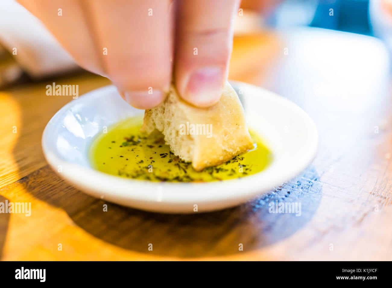 Die Hand des Menschen eintauchen Scheibe Brot in herbed Olivenöl im Restaurant Stockfoto