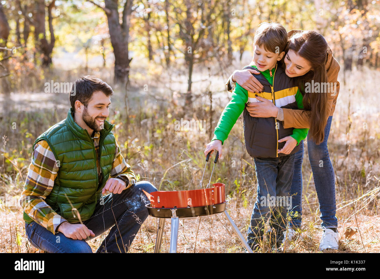 Portrait der glücklichen Familie mit einem Kind vorbereiten Barbecue Grill im Herbst Park Stockfoto