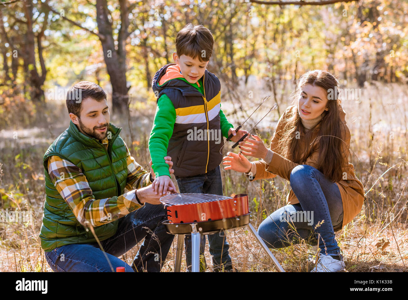 Portrait der glücklichen Familie mit einem Kind vorbereiten Barbecue Grill im Herbst Park Stockfoto