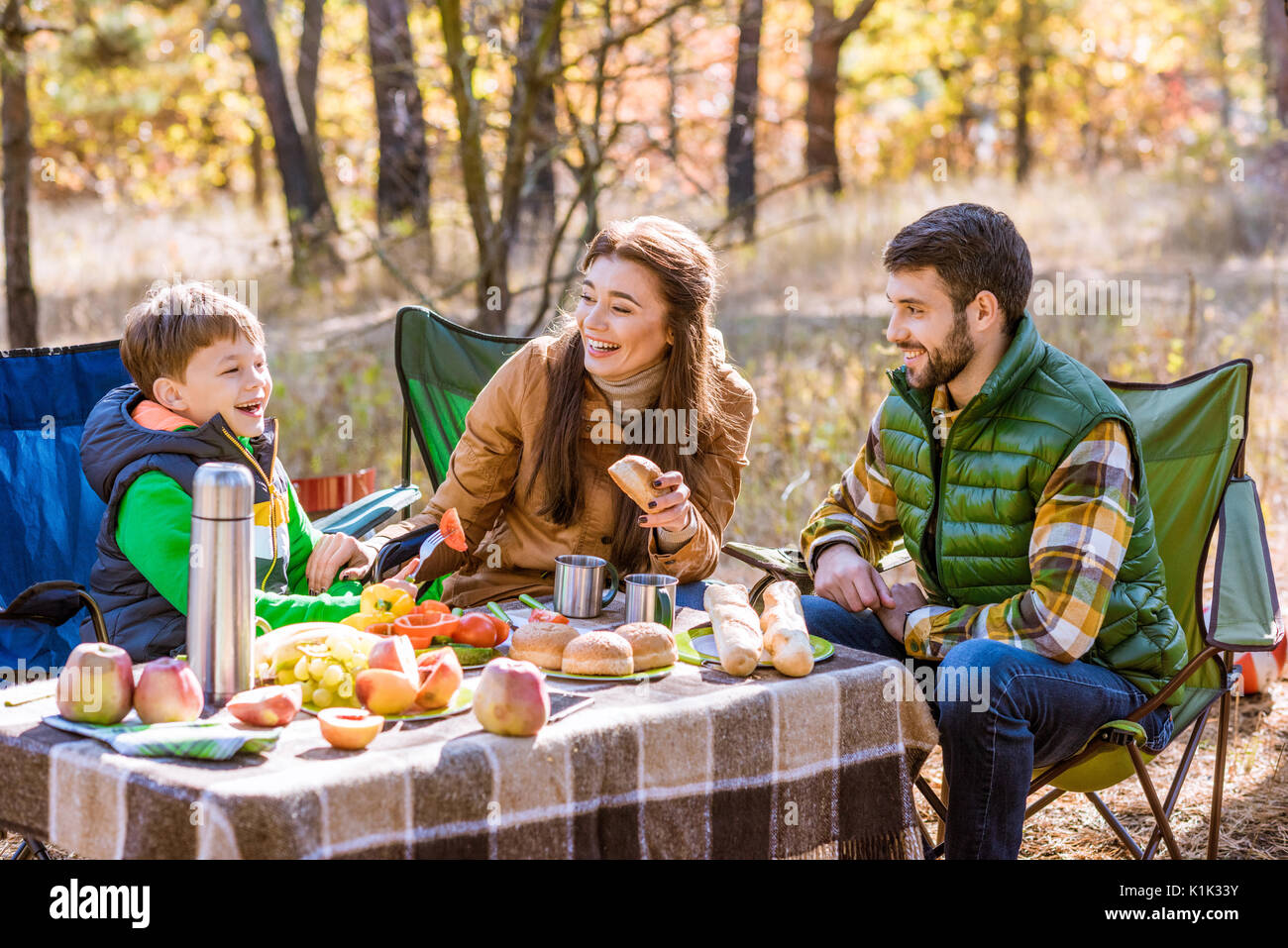 Glücklich lächelnde Familie essen und Spaß beim am Tisch sitzen auf Picknick im Herbst Wald Stockfoto