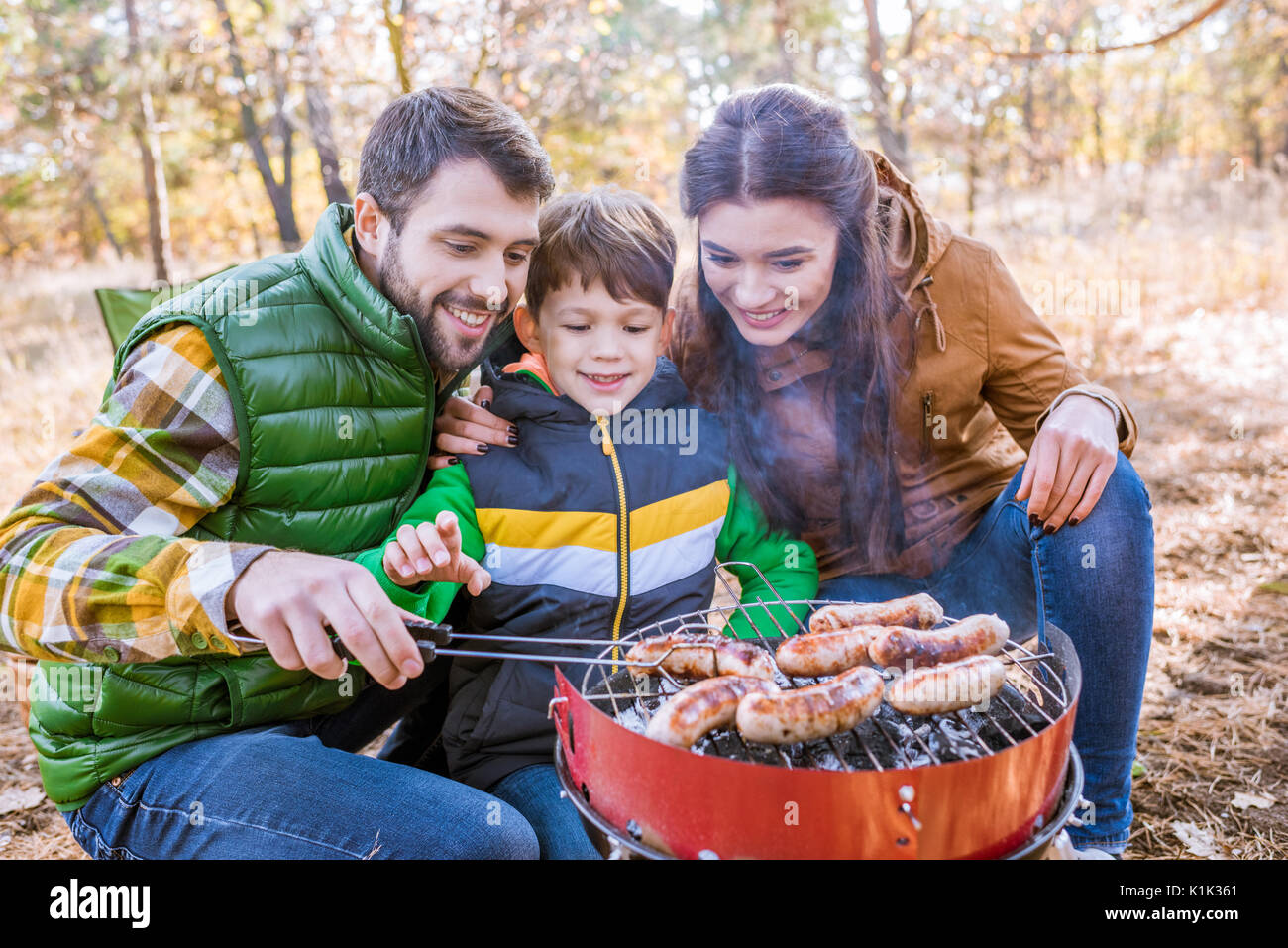 Fröhliche Eltern mit niedlichen kleinen Sohn grillen Würstchen auf Grill im  Herbst Park Stockfotografie - Alamy