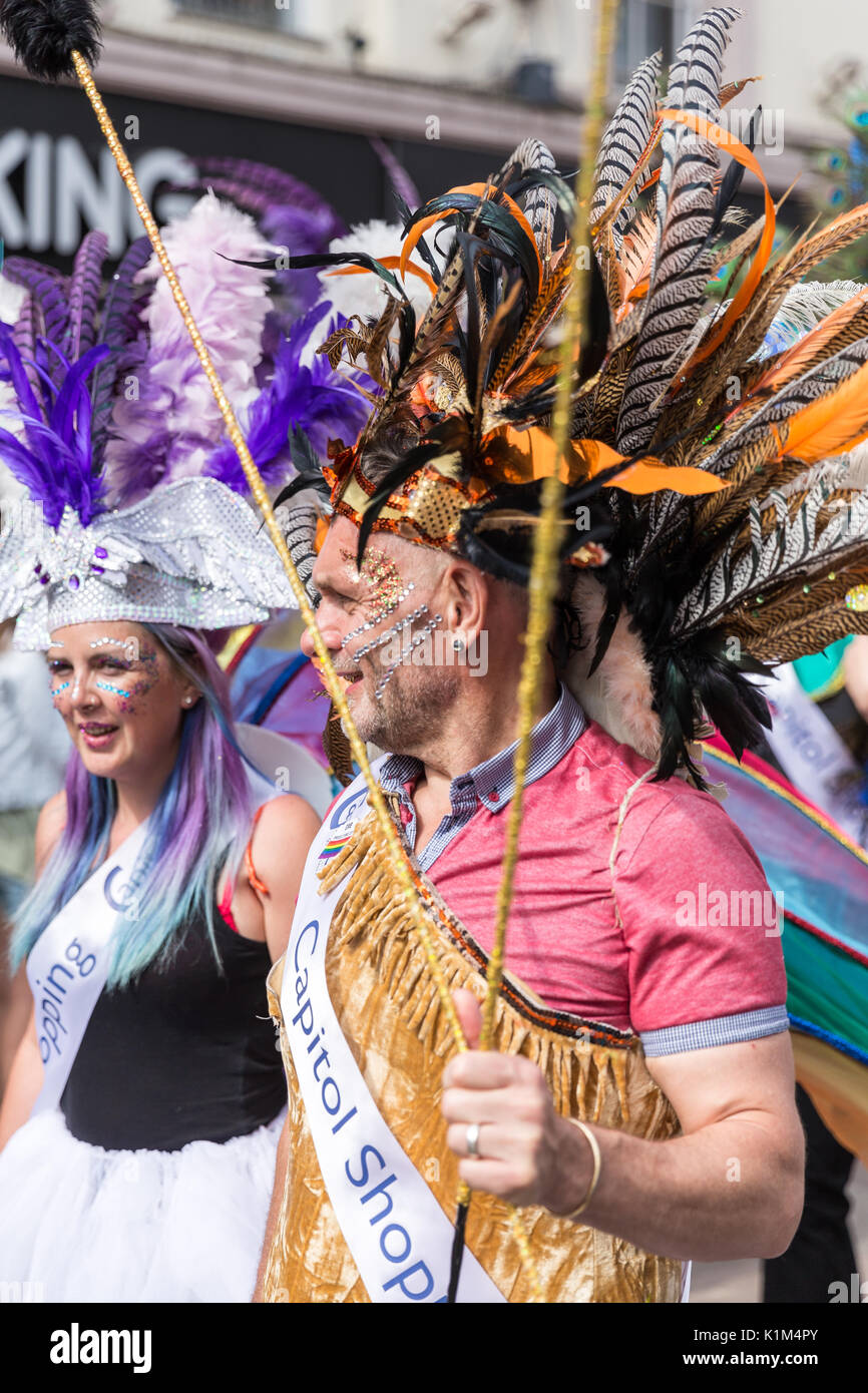 Ein Mann und eine Frau März in Cardiff Pride Parade mit einer Kopfbedeckung der Federn Stockfoto
