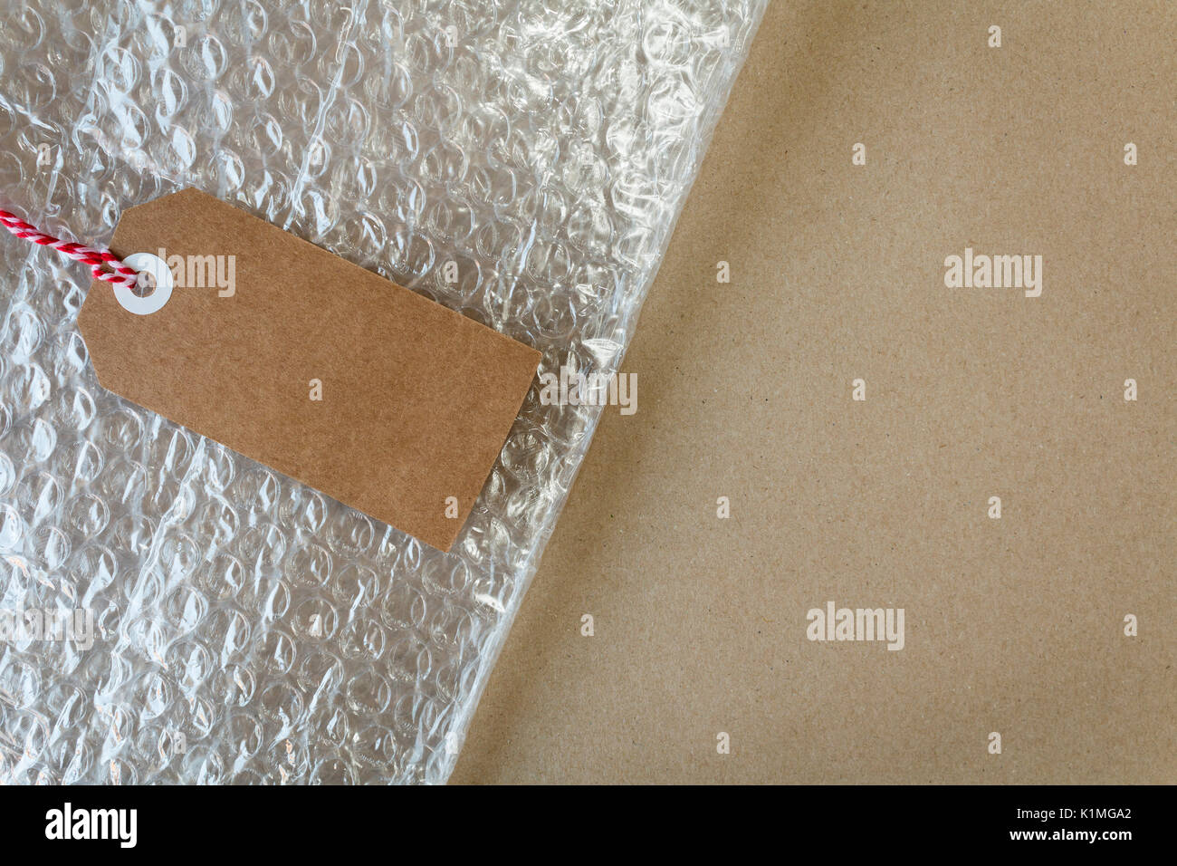 Verpackung und Materialien mit Luftpolsterfolie und ein Geschenk tag auf braunem Packpapier mit Copyspace Stockfoto