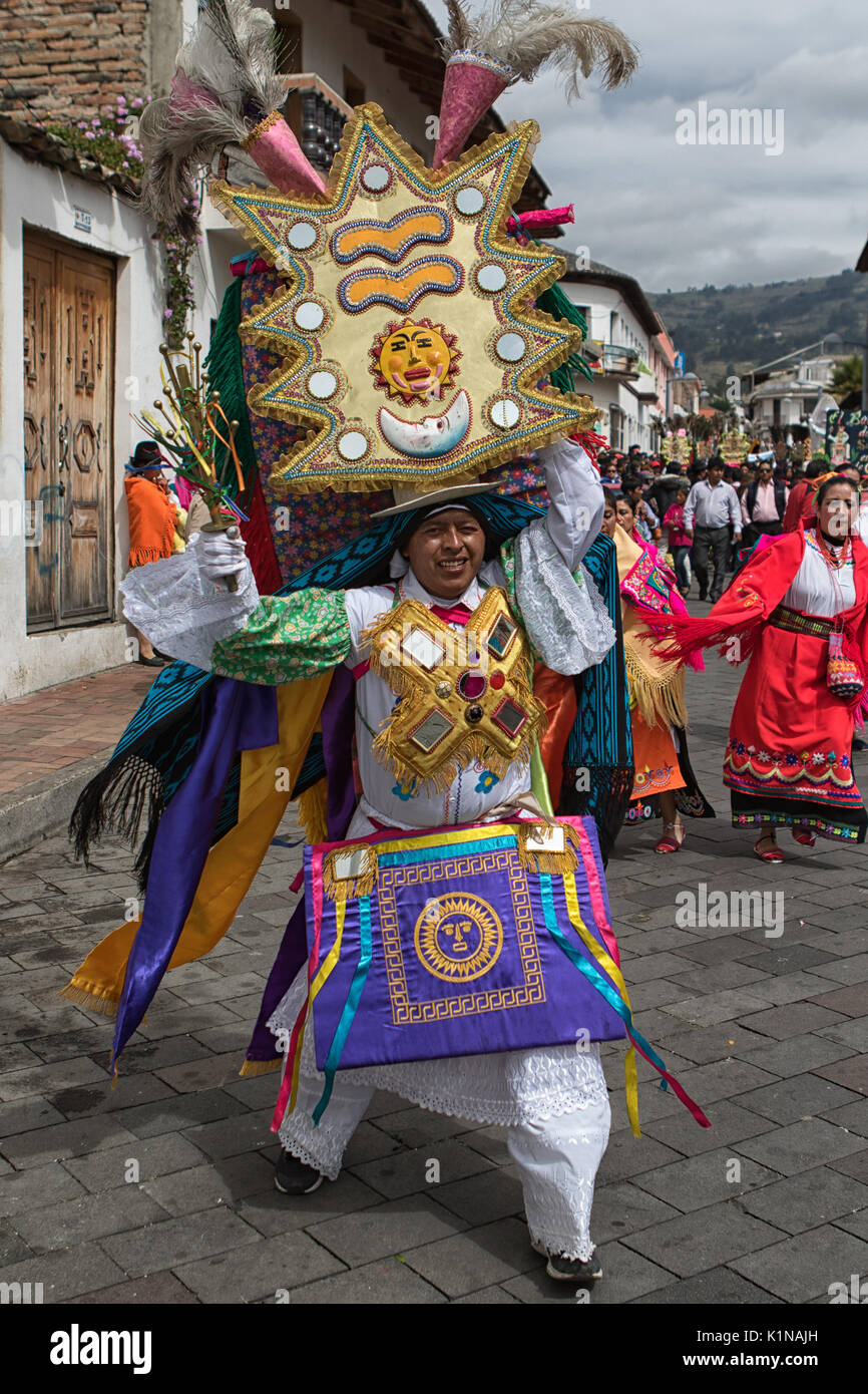 Juni 18, 2017 Pujili, Ecuador: Indigene kichwa Mann tanzen auf der Straße in traditioneller Kleidung Balancing ein großes Display auf seinem Kopf in Corpus Christi Stockfoto