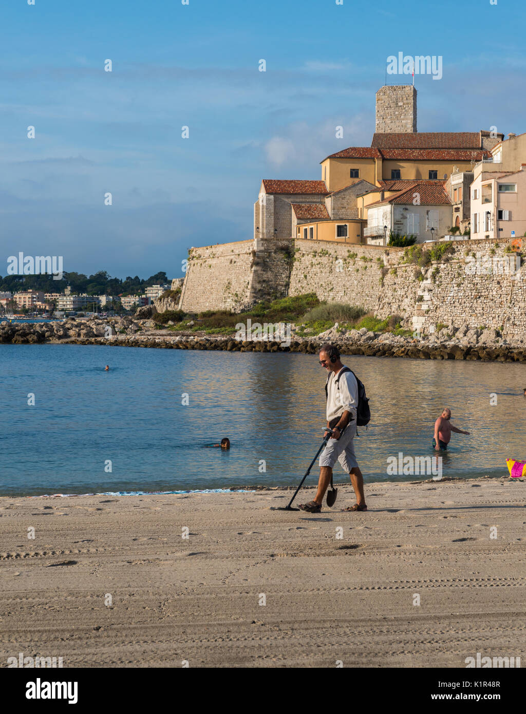Ein Mann mit einem Metalldetektor am Strand mit Blick auf Antibes, Cote d'Azur, Frankreich Stockfoto