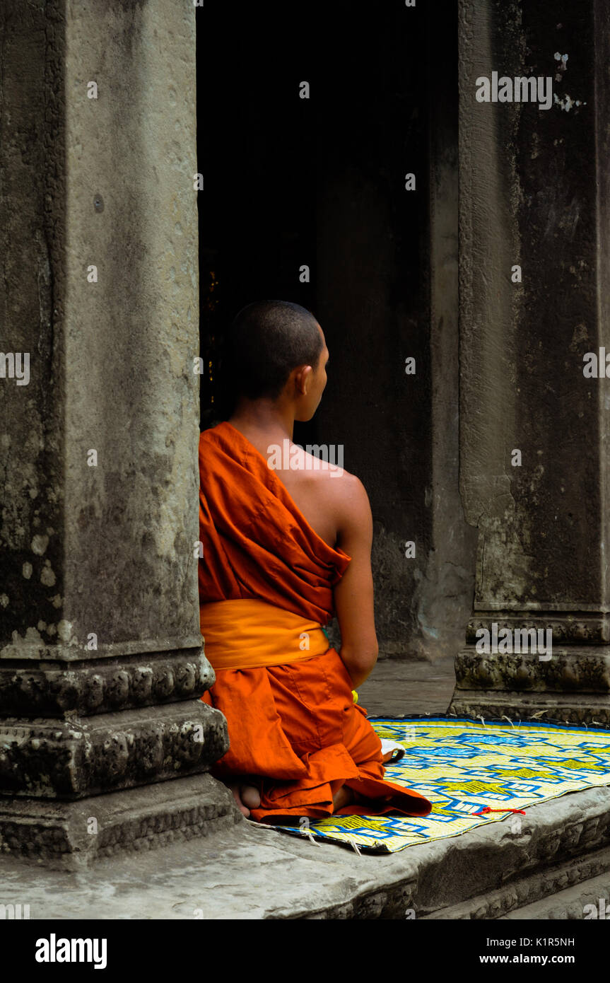 Ein buddhistischer Mönch in der Nähe einen Tempel Spalte beim Warten auf den nächsten Anhänger für Gebet und Segen am Tempel Angkor Wat, Kambodscha zu kommen. Stockfoto