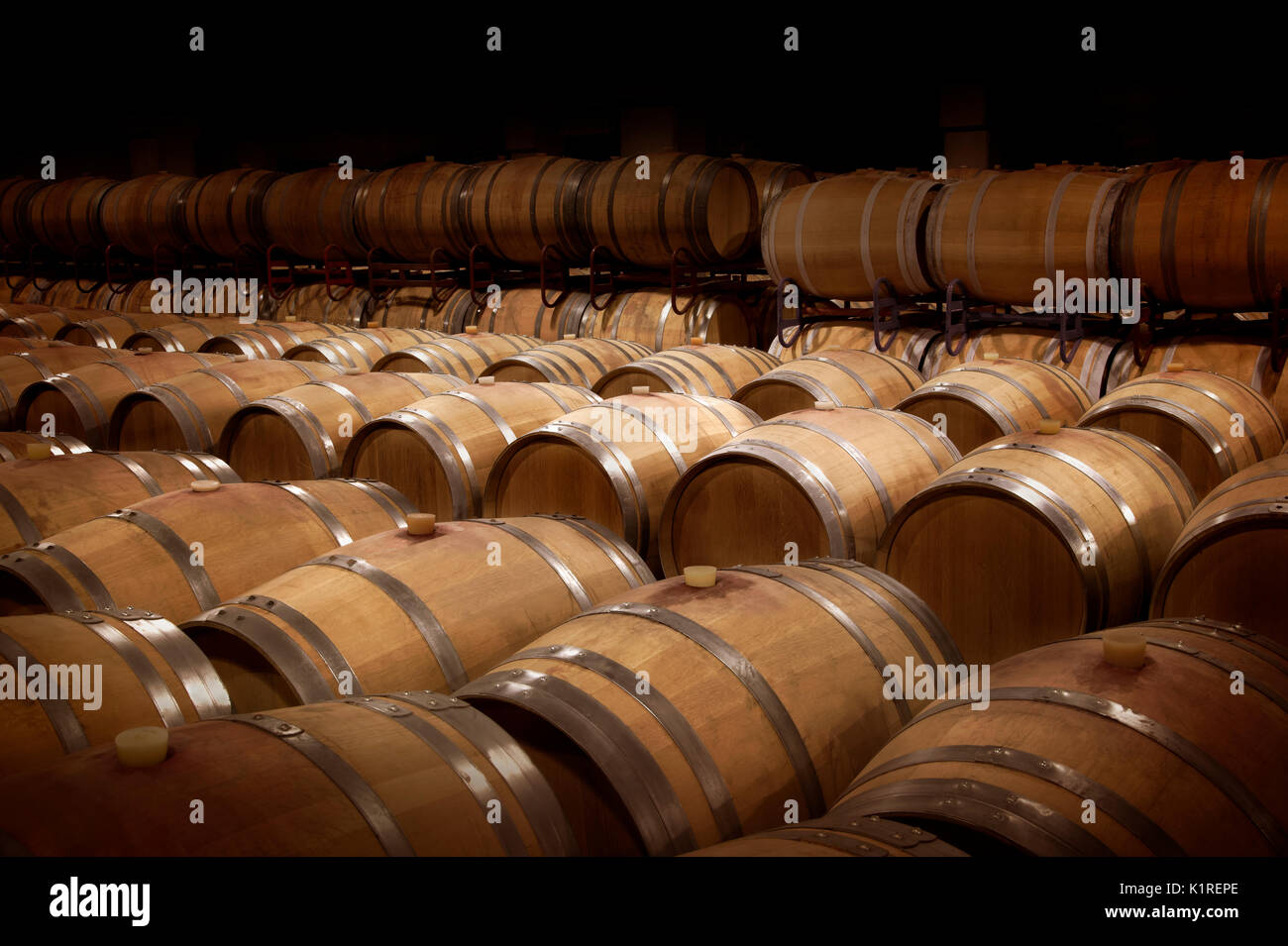 Weinkeller in warmem Ambiente. Reihen von Holz- Weinfässer in einem Weingut. Stockfoto