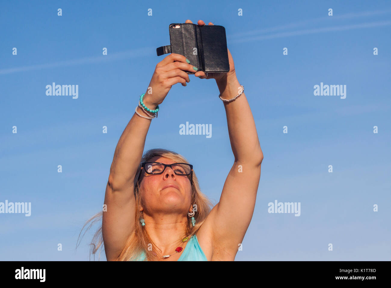 Eine junge Frau nimmt Fotos Videos mit dem Handy am Strand. Stockfoto