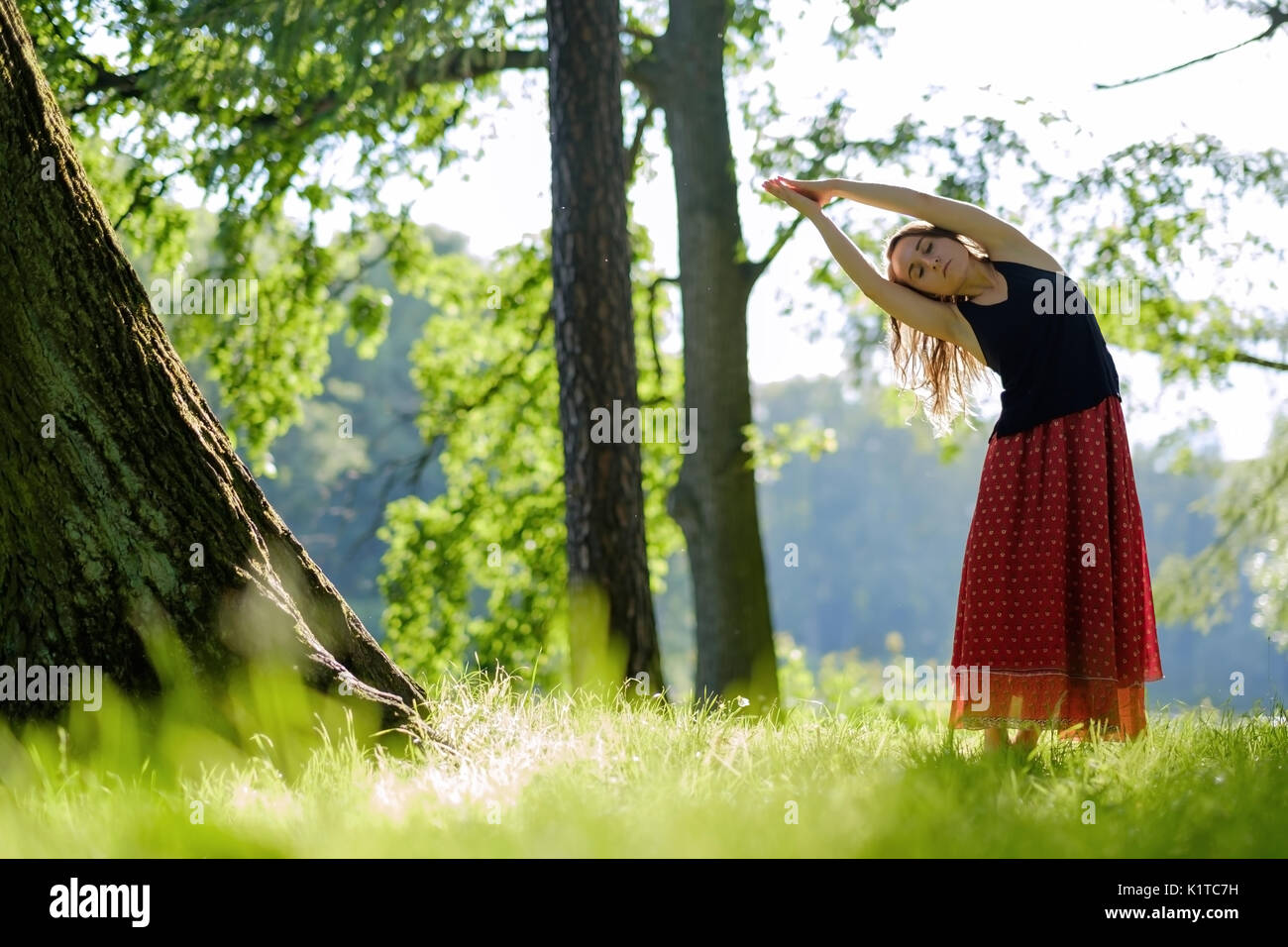 Attraktive junge Frau im roten Rock ist Yoga, asana am Morgen. Stockfoto