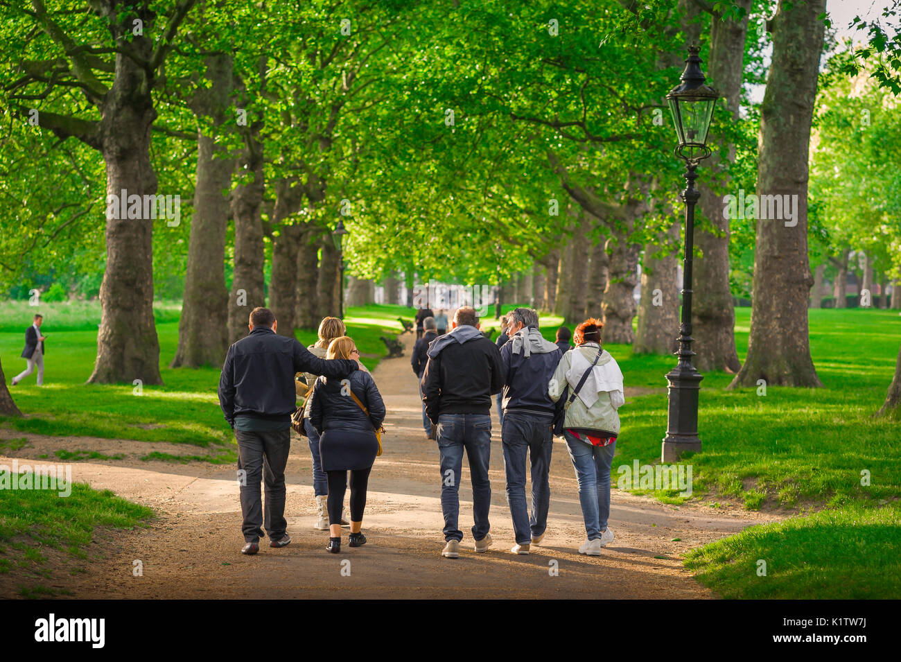 Freunde zusammen spazieren, Blick auf eine Gruppe von Freunden mittleren Alters, die an einem Sommernachmittag durch den Green Park im Zentrum Londons schlendern, England, Großbritannien. Stockfoto