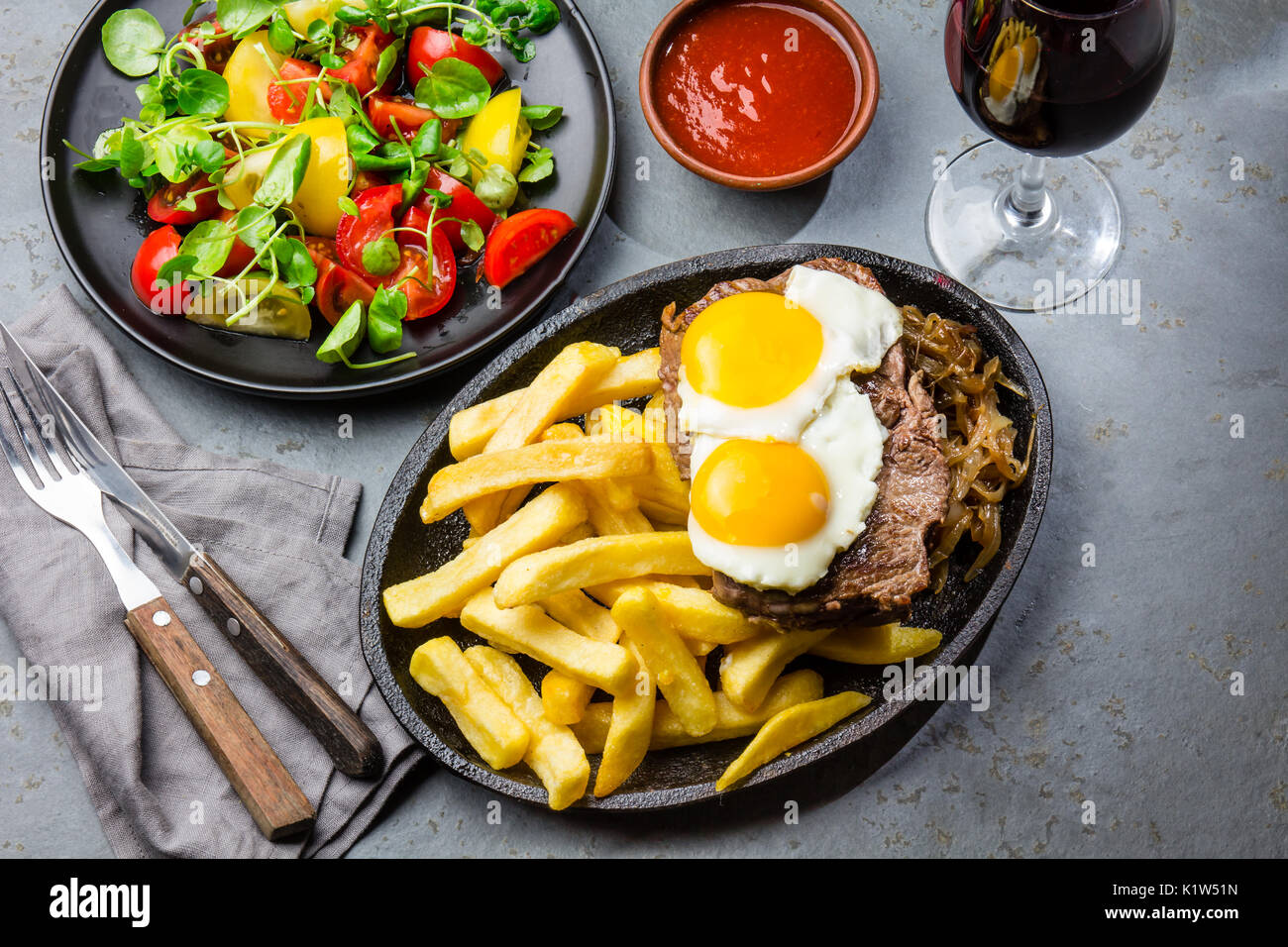 Peruanische Lateinamerikanische Küche. Lomo a lo Pobre. Rinderfilet mit Bratkartoffeln Pommes und Ei serviert mit Chile Sauce und Wein Stockfoto