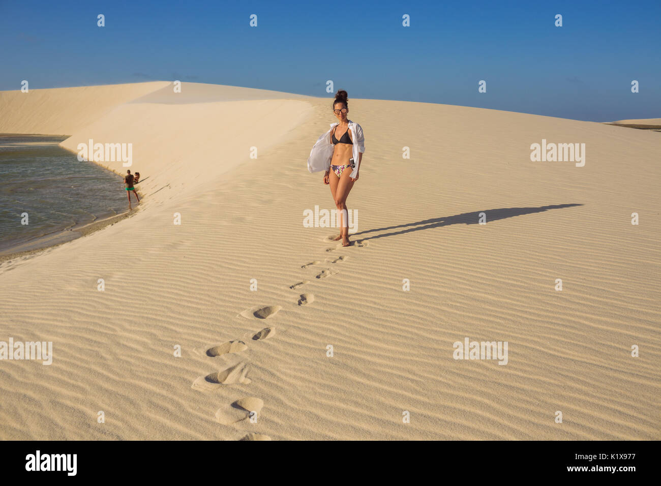 Caucasic Frau posiert mit offenem Hemd und Bikini in einer natürlichen regen See Oase zwischen de Dünen in der Nähe von Lagoa Azul, Jericoacoara, Ceará, Brasilien Stockfoto