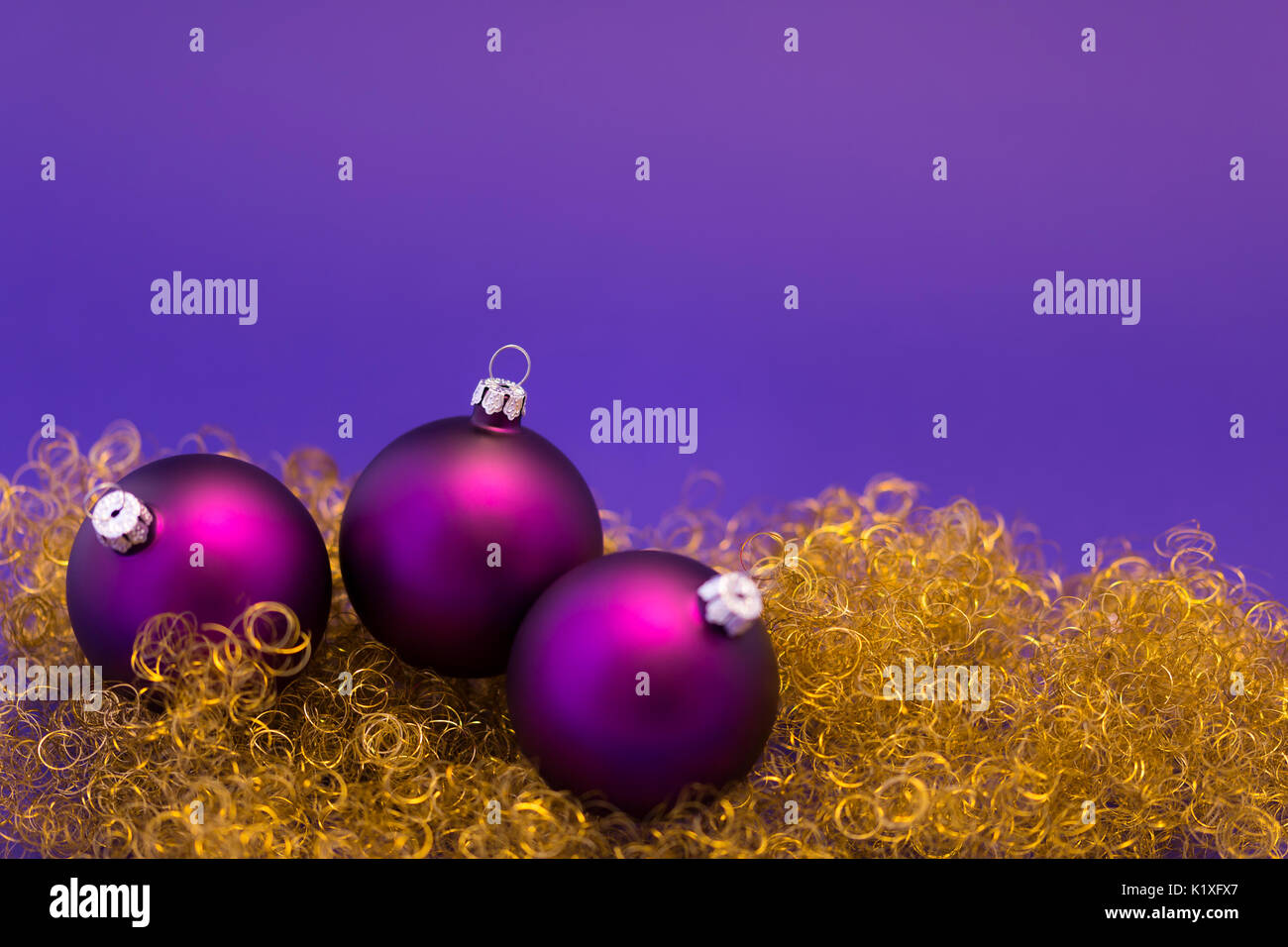 Schöne lila Weihnachtskugeln mit satin-Effekt auf gold-Glitter und lila Hintergrund. Stockfoto