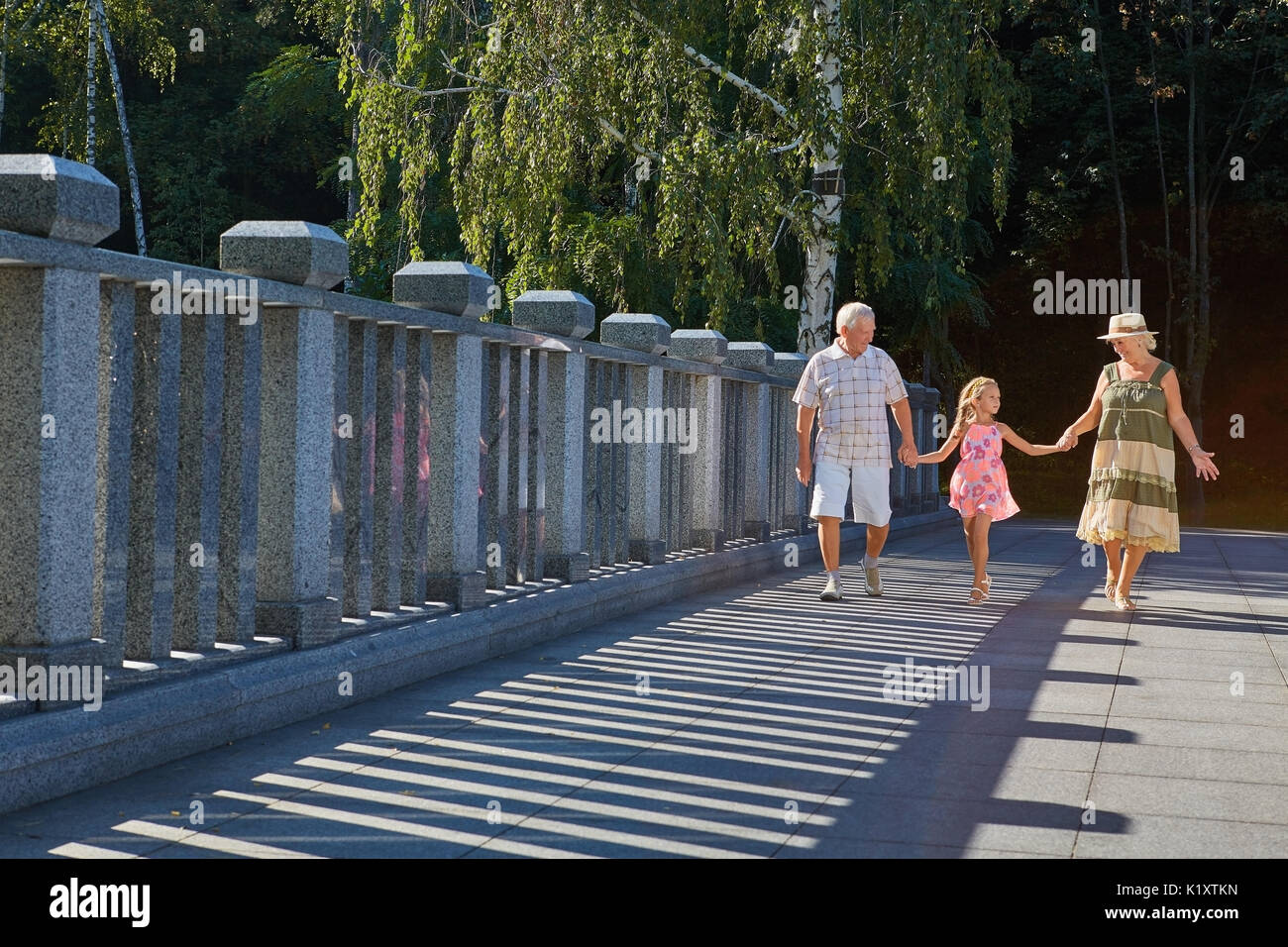 Mädchen mit Großvater und Großmutter. Familie wandern, Sommertag. Bei einem Spaziergang durch den Park. Stockfoto