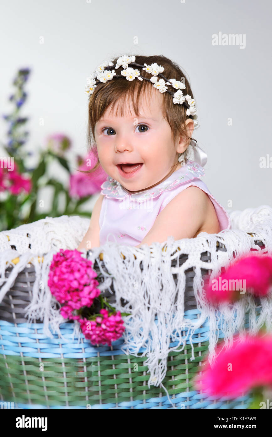 Schönes kleines Kind sitzt mit einer Blume, grauen Hintergrund. Stockfoto