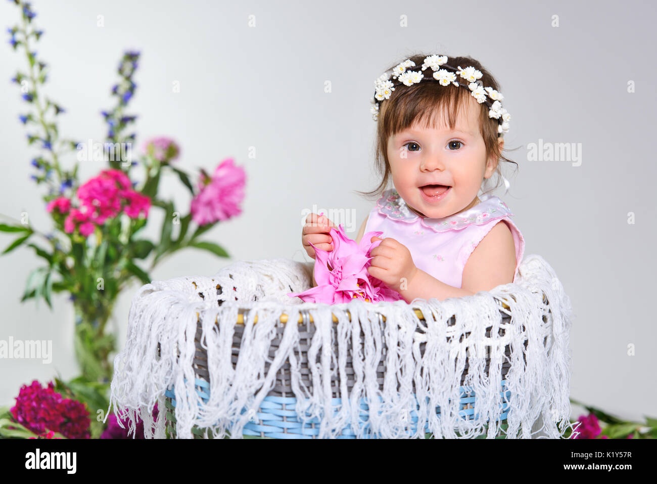 Schönes kleines Kind sitzt mit einer Blume. Stockfoto
