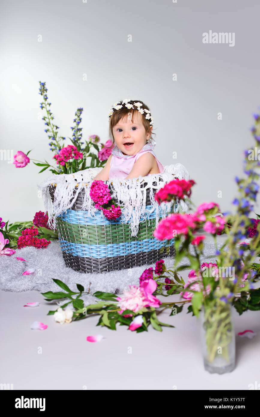 Schönes kleines Kind sitzt mit einer Blume. Stockfoto