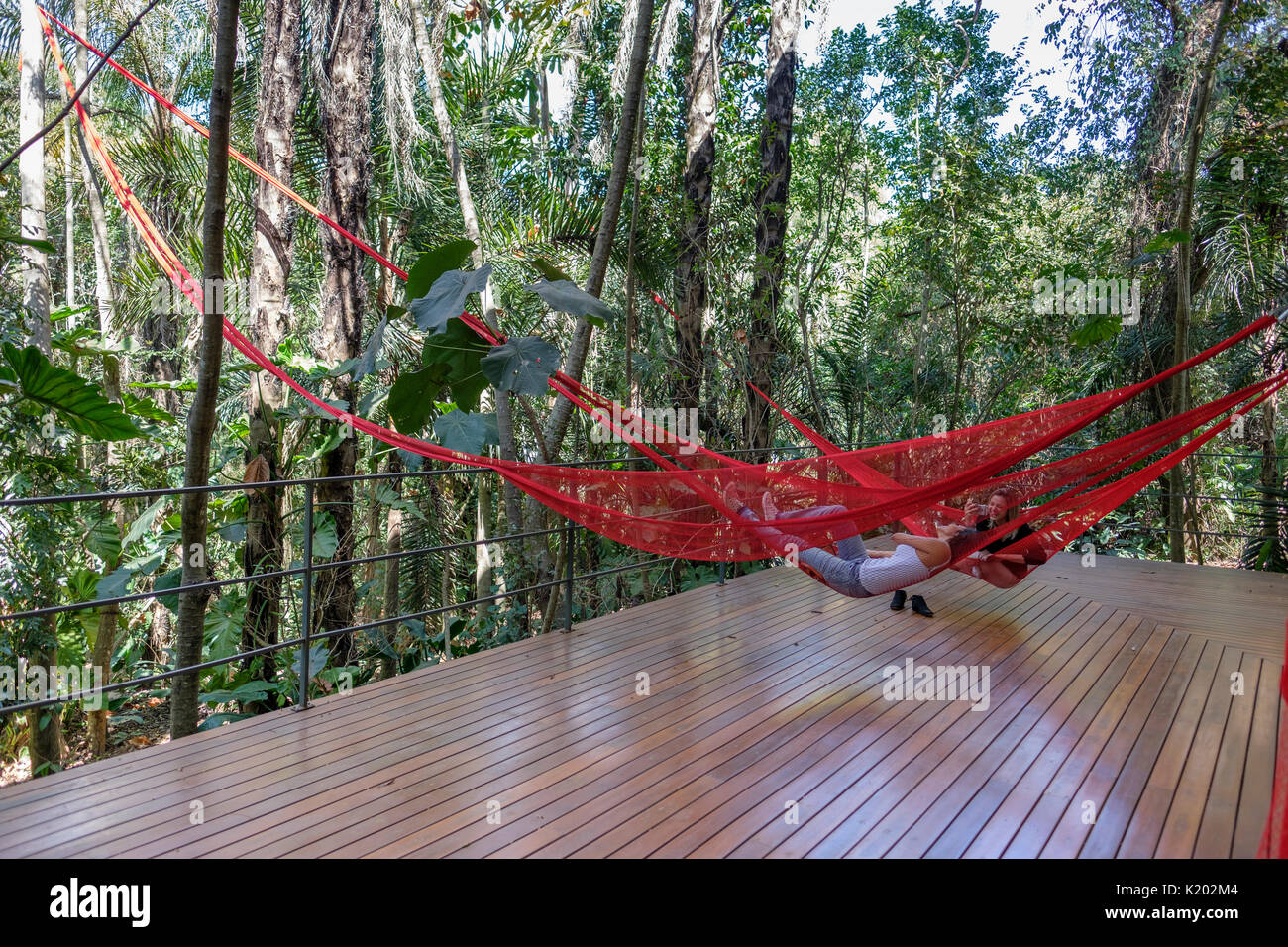 Menschen, die auf roten Hängematten hängen, hängen an der malerischen Tunga Gallery, Inhotim Cultural Institute, Brumadinho, Belo Horizonte, Minas Gerais, Brasilien. Stockfoto