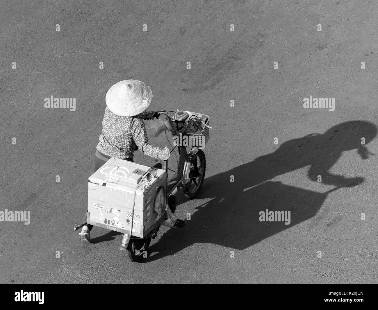 Straßenhändler mit Schatten ist lange auf der Straße, als ob er sagen Schwierigkeiten bei der Art und Weise der Lebensstandard der arbeitenden Armen ländlichen Gebieten in Vietnam. Stockfoto
