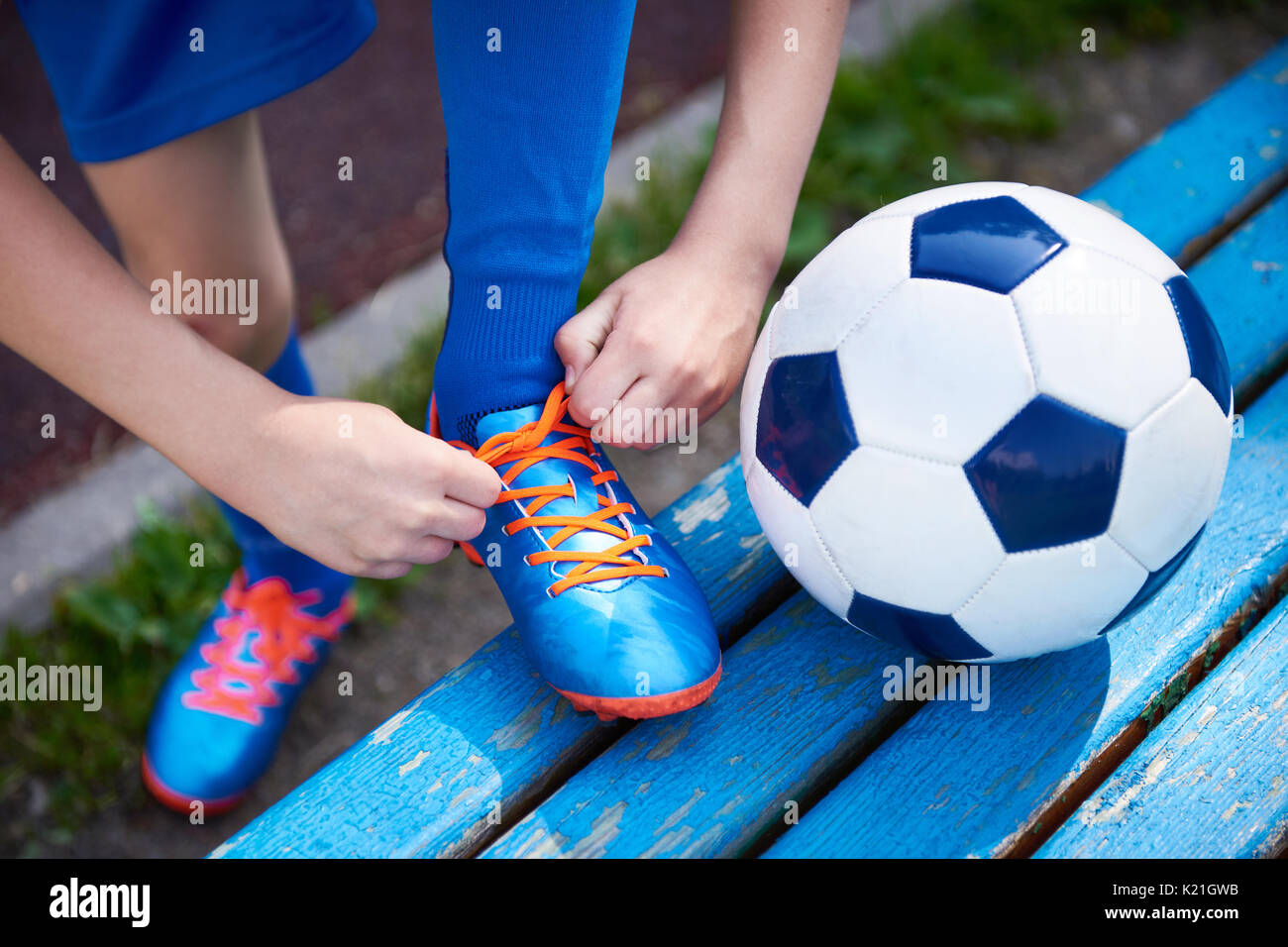 Jungen Fußball Fußball Binden der Schnürsenkel auf die Stiefel auf der Werkbank Stockfoto