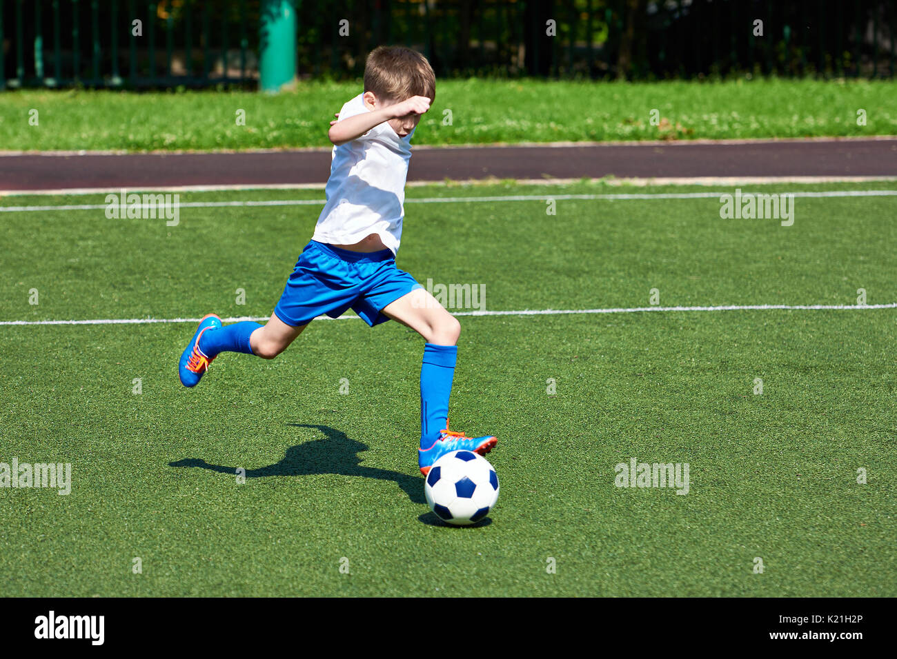 Junge Fußball-Spieler läuft mit dem Ball auf dem grünen Rasen des stadiumм Stockfoto