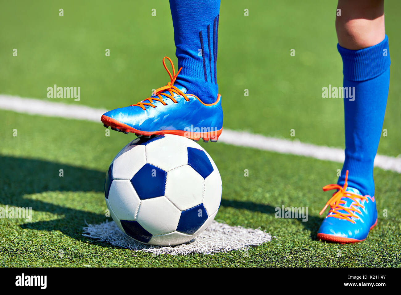 Fuß eines Fußball-Spieler in einem Fußballschuh, der auf einer Kugel auf einer künstlichen grünen Rasen des Stadions Stockfoto