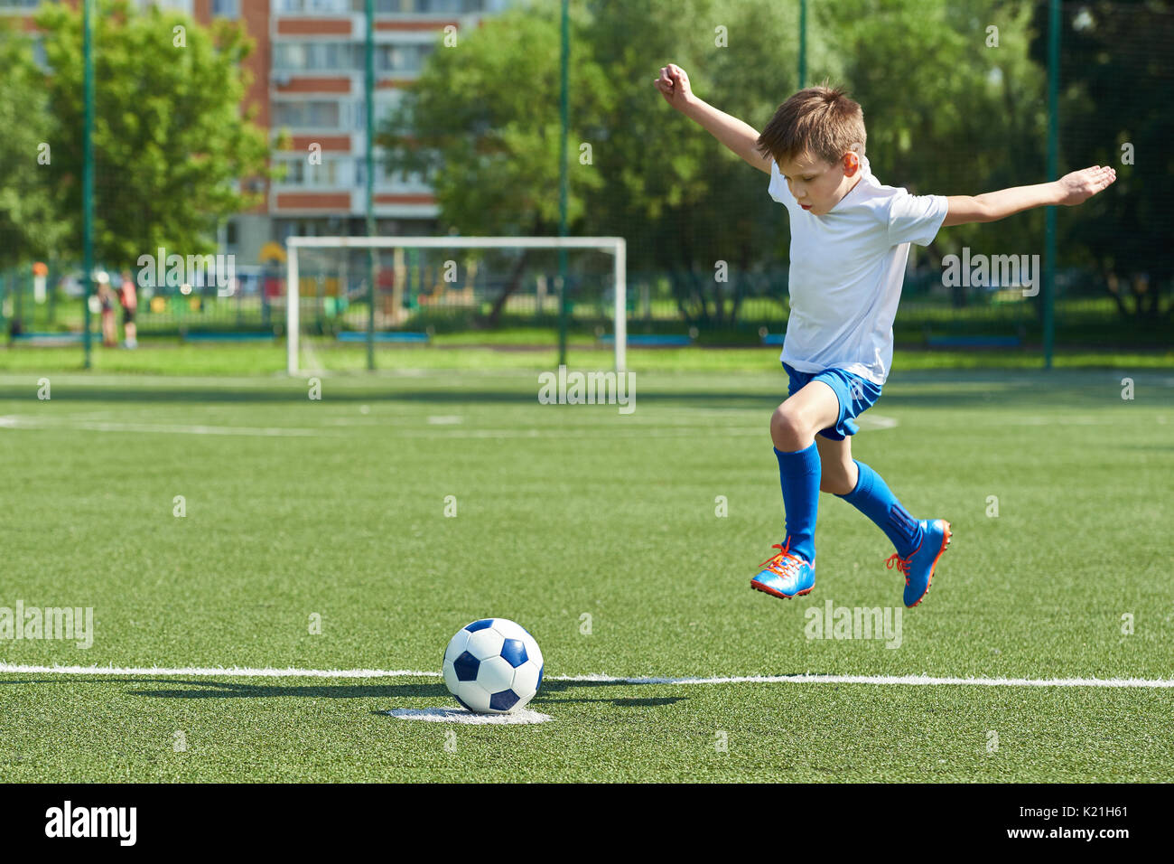 Junge Fußballer mit einem Sprung vor einen Kick auf der Kugel Stockfoto