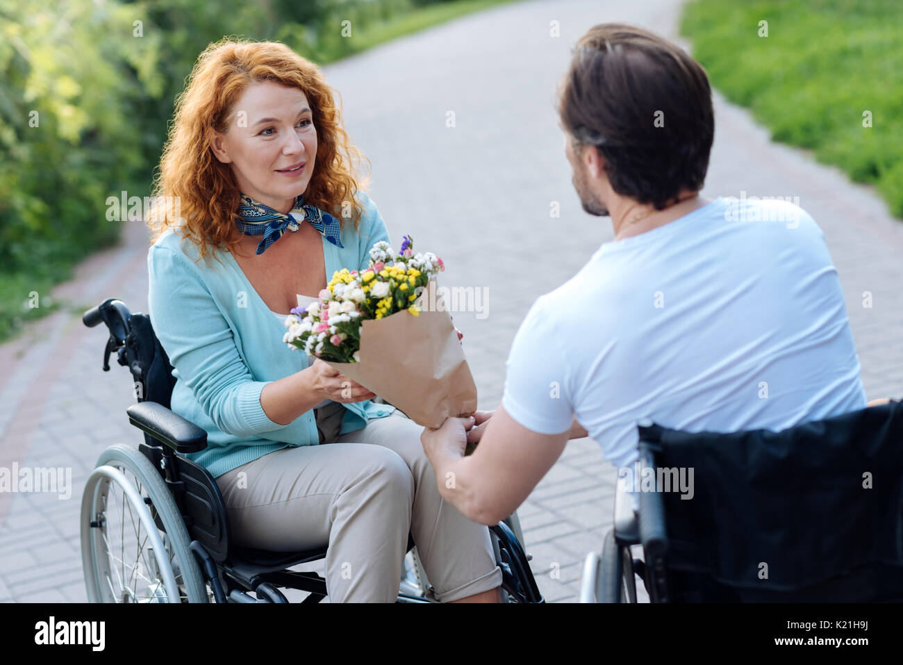 Schönes älteres wheelchaired Frau noch einen Haufen Blumen Stockfoto