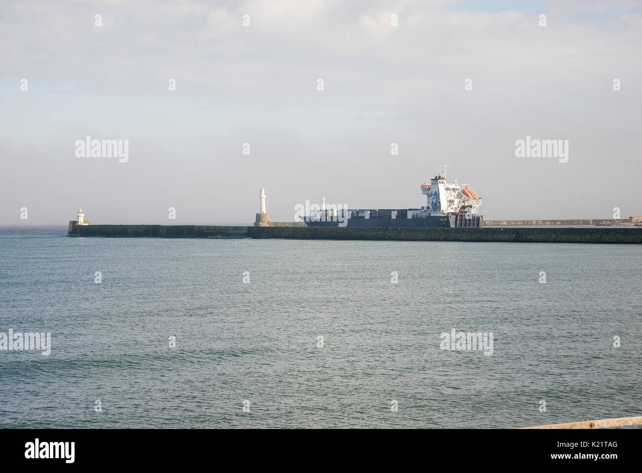 Ein Frachtschiff Abfahrt Aberdeen Hafen zwischen zwei Leuchttürme an der Hafeneinfahrt Stockfoto
