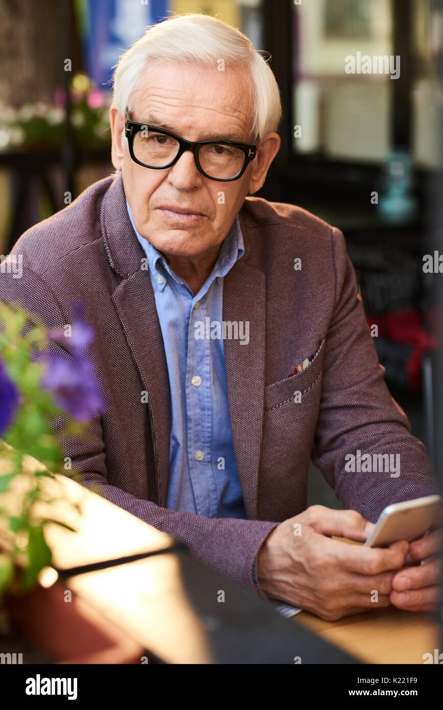 Nachdenklich, älterer Mann mit Smartphone im Cafe Stockfoto