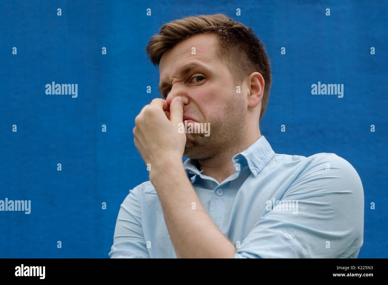 Porträt der jungen kaukasischen Mann seine Nase schließen wegen der schrecklichen riechen Stockfoto