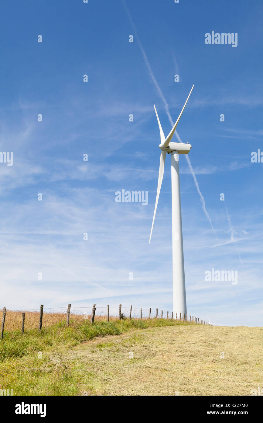 Windenergieanlage auf einem Hügel in einer frisch geernteten agricutltural Feld mit einem rustikalen hölzernen Zaun in einem Konzept der natürlichen Ressourcen und der erneuerbaren Energien. Stockfoto