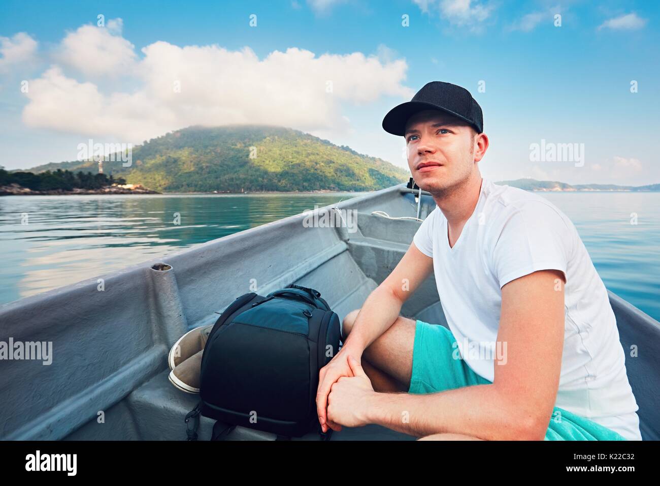 Seitenansicht der junge Mann während der Fahrt im Boot auf dem Meer gegen tropische Inseln und blauer Himmel. Stockfoto