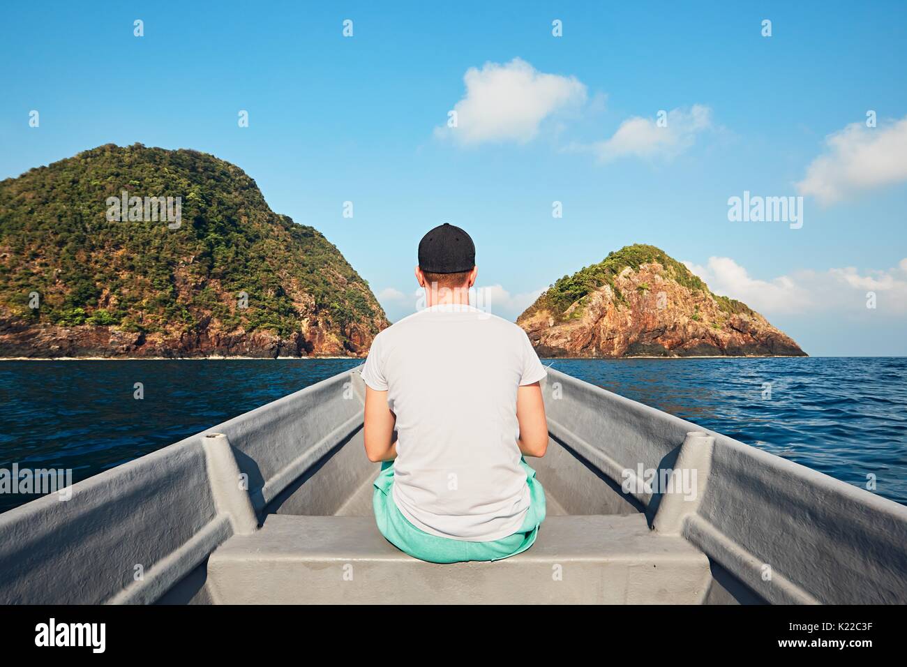 Ansicht der Rückseite des jungen Mann unterwegs im Boot auf dem Meer gegen tropische Inseln und blauer Himmel. Stockfoto