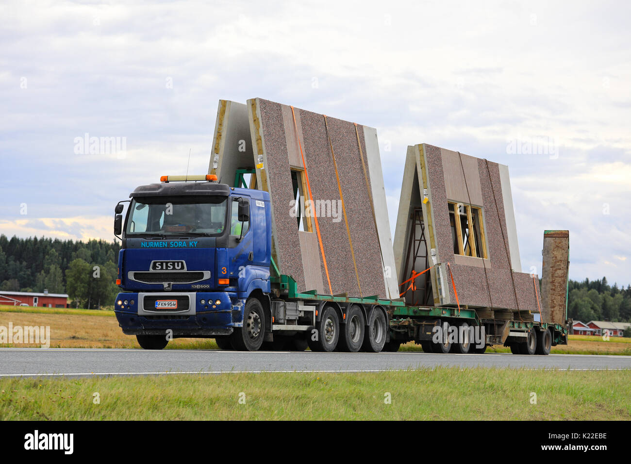 JOKIOINEN, Finnland - 25. AUGUST 2017: Blau Sisu E 500 von Nurmen Sora Ky transportiert Betonfertigteile bau Elemente entlang der Autobahn an einem bewölkten Tag Stockfoto