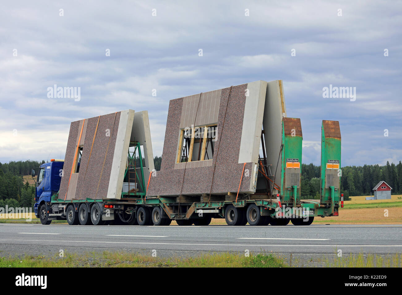 JOKIOINEN, Finnland - 25. AUGUST 2017: Blau Sisu E500 transportiert Betonfertigteile bau Elemente entlang der Autobahn an einem bewölkten Tag der Spätsommer. Stockfoto