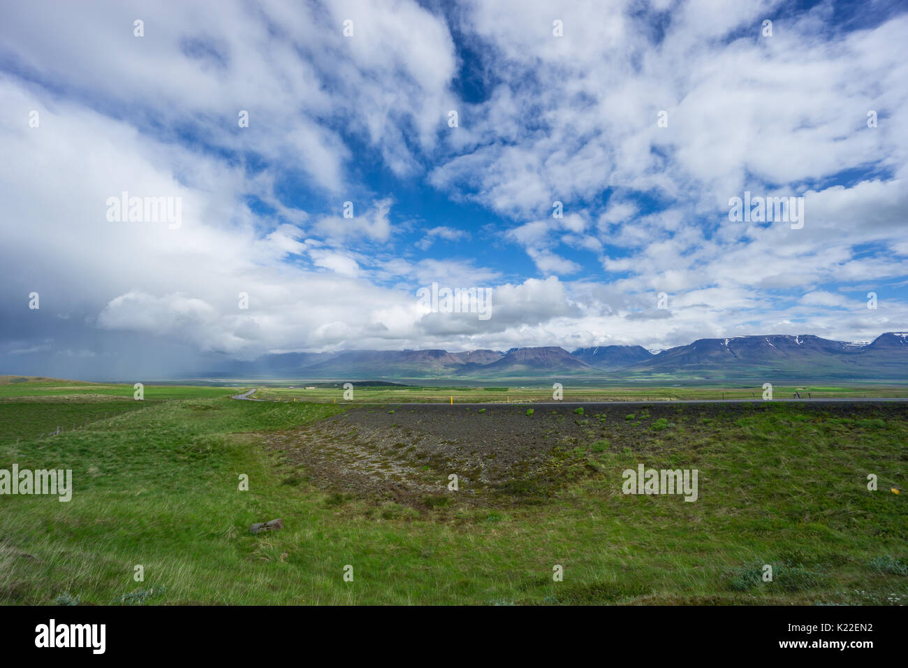 Island - unglaublich bunte Landschaft mit grünen Wiesen und schneebedeckten Bergen und Straße Stockfoto